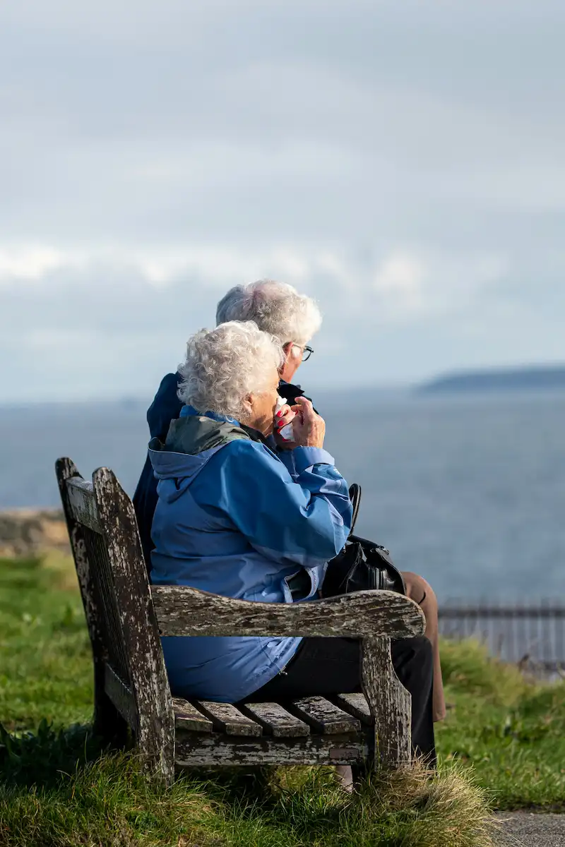 Older couple seated by the sea—gentle black car service for seniors.