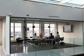 Executives & Assistants having a meeting in an office of glass walls